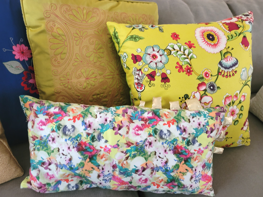Throw pillow cushions on a sofa. One rectangle in floral print, a square one in floral print fabric. The third one has a Moroccan tile pattern.