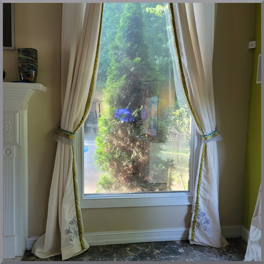 Window curtain in off white with blue flower embroidery. Curtain tie backs in green chartreuse fabric.