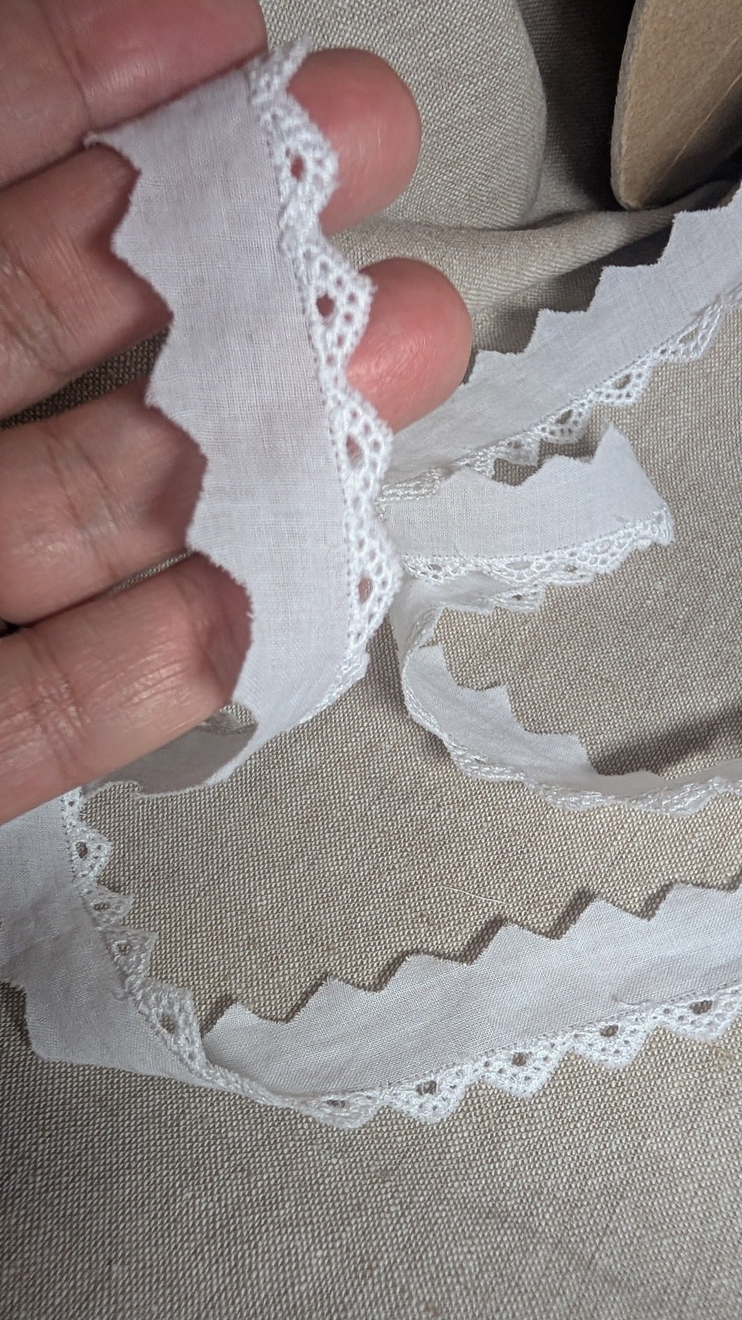 Close up of white Swiss cotton edging held by hand. Trim brand Martha Pullen