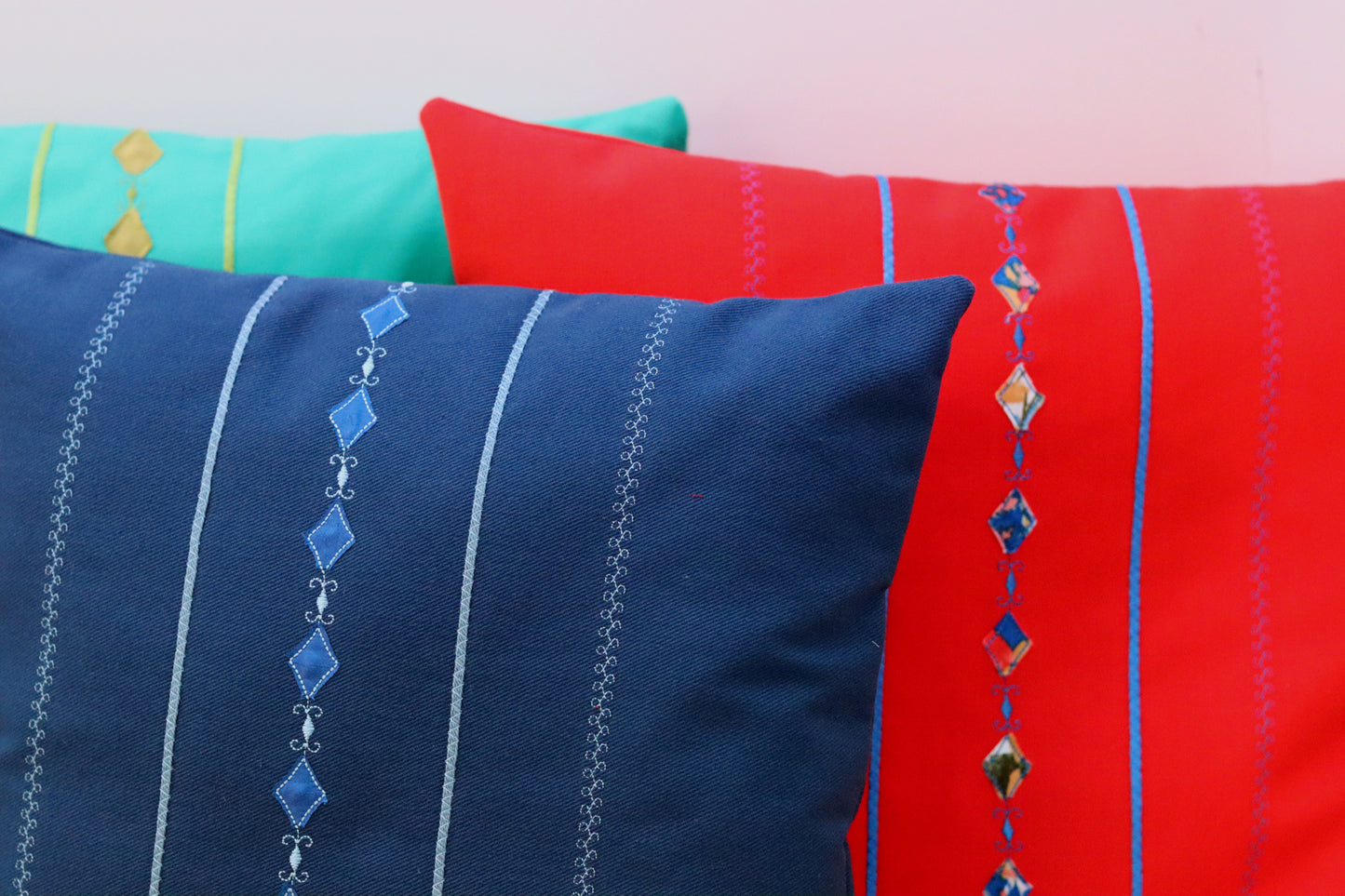 Three throw pillow covers in green, orange and blue.