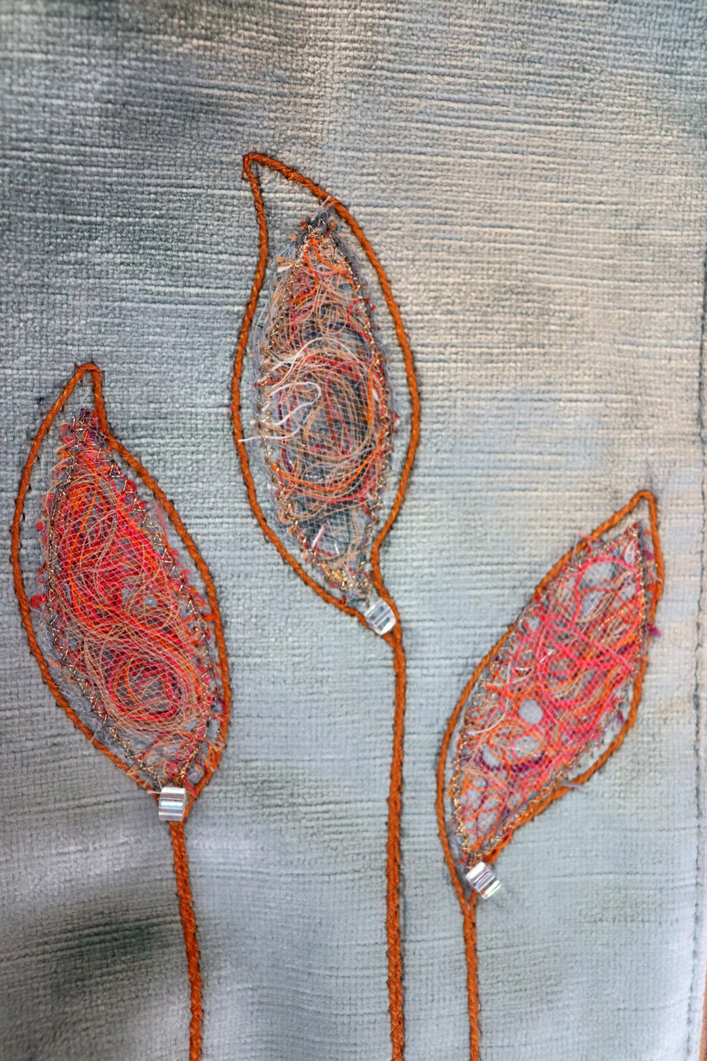 Details of appliqué leaves in gray and orange of grayish and blue handbag clutch