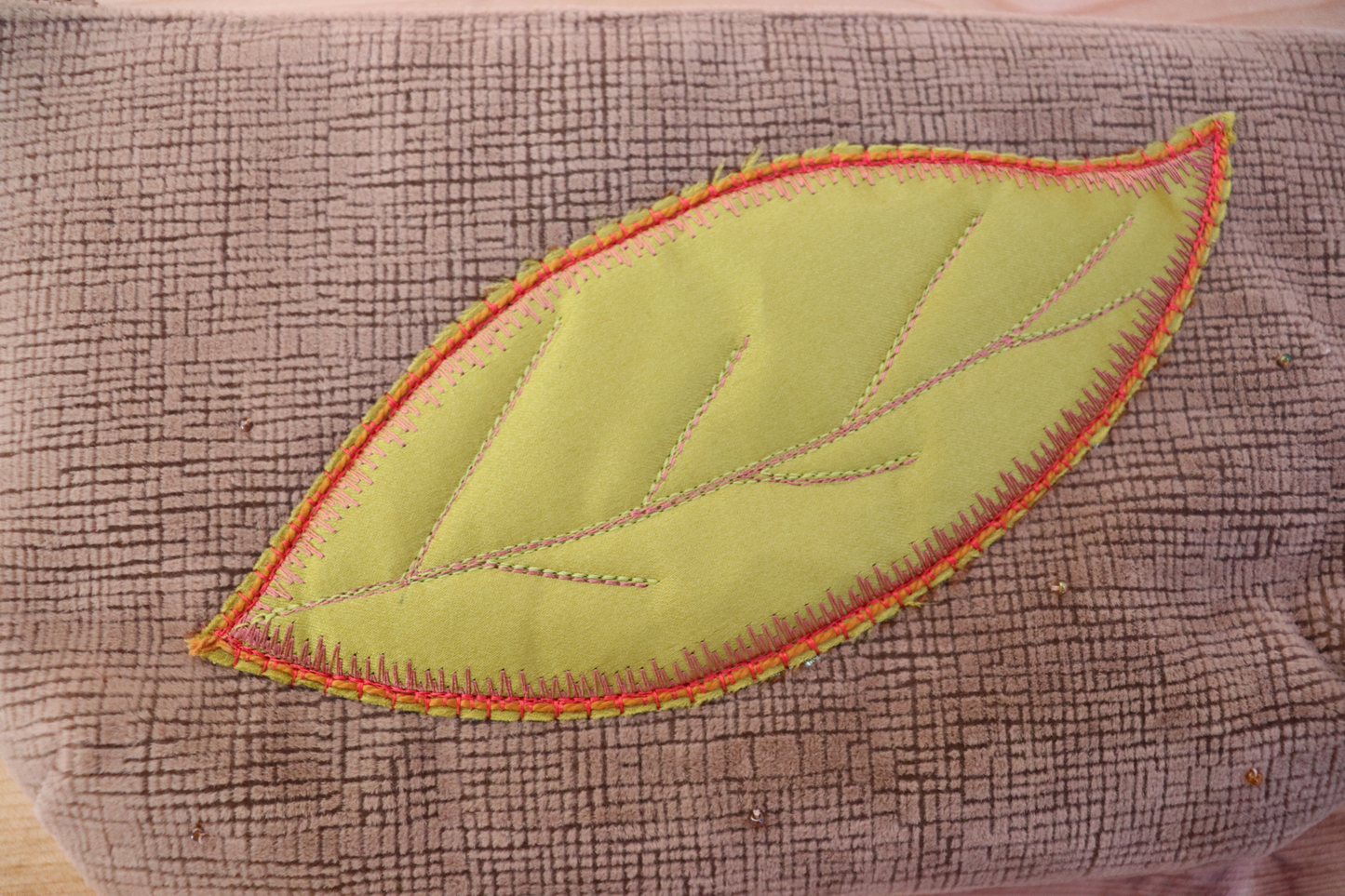 Detail of green appliqué on blush pink handbag clutch