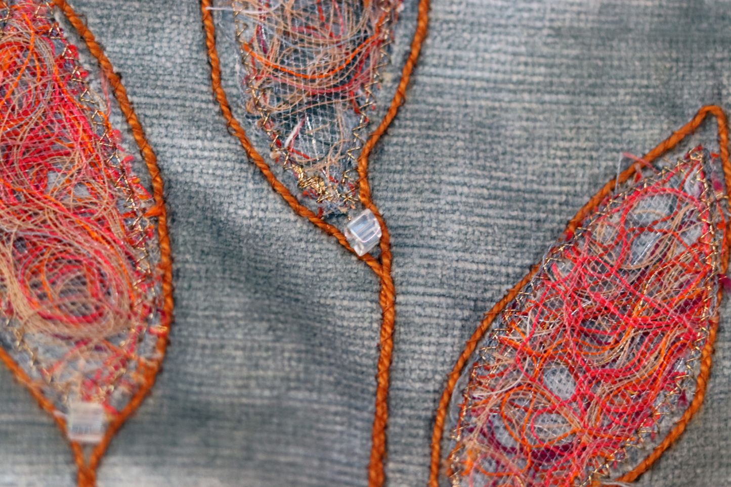Appliqué detail in gray and orange threads