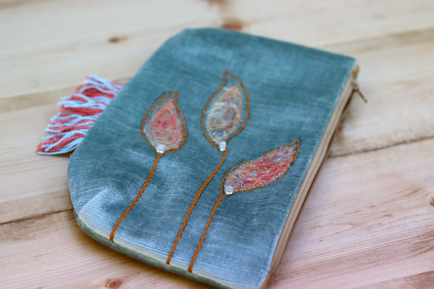 Detail of grayish blue fringe handbag with leaf appliqué