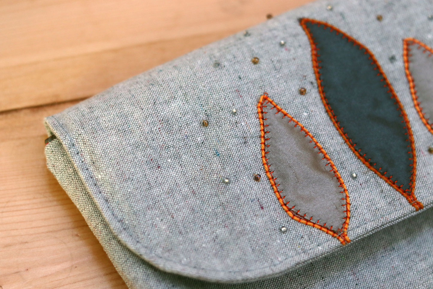 other detail of of the appliqué of the gray flap handbag clutch