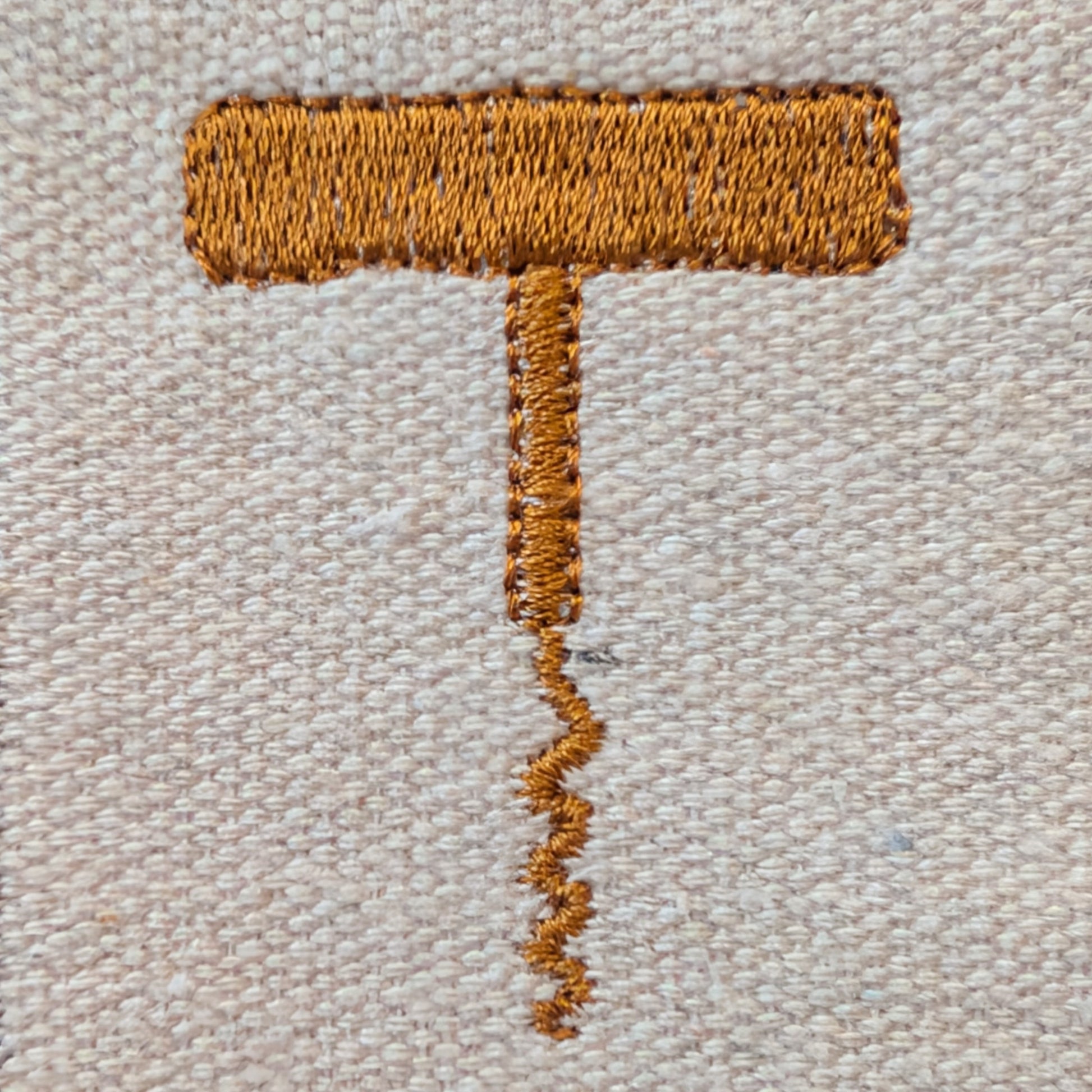Embroidered corkscrew on a textured beige fabric background