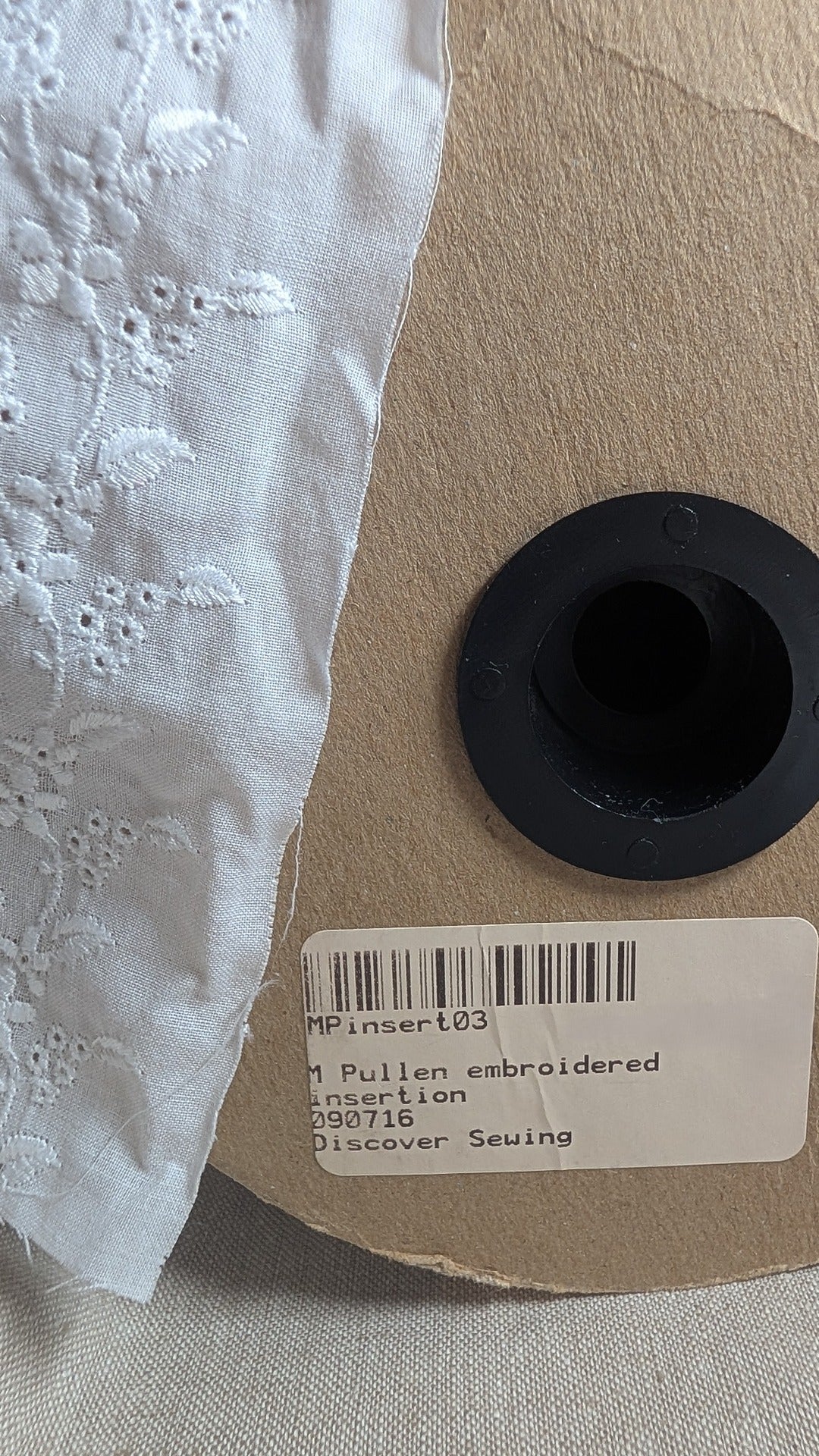 Close-up of Swiss embroidery cotton trim in white from Martha Pullen showing floral motif, product label