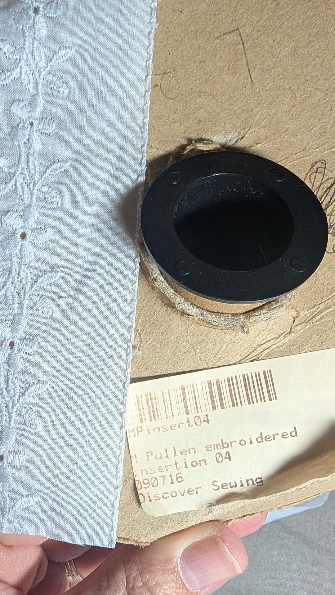 Close- up Swiss embroidery cotton trim from Martha Pullen in white with flower motif. Showing original product label.