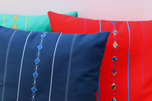Three throw pillow covers in green, orange and blue.
