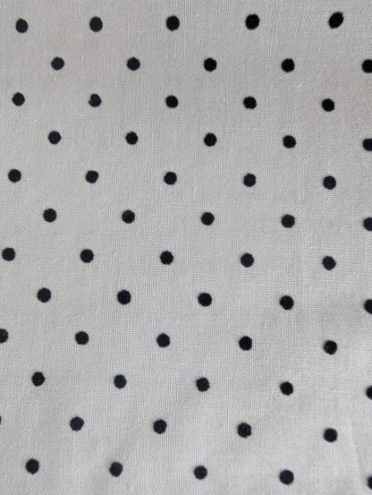 Close-up of fabric with black polka dots on a white background