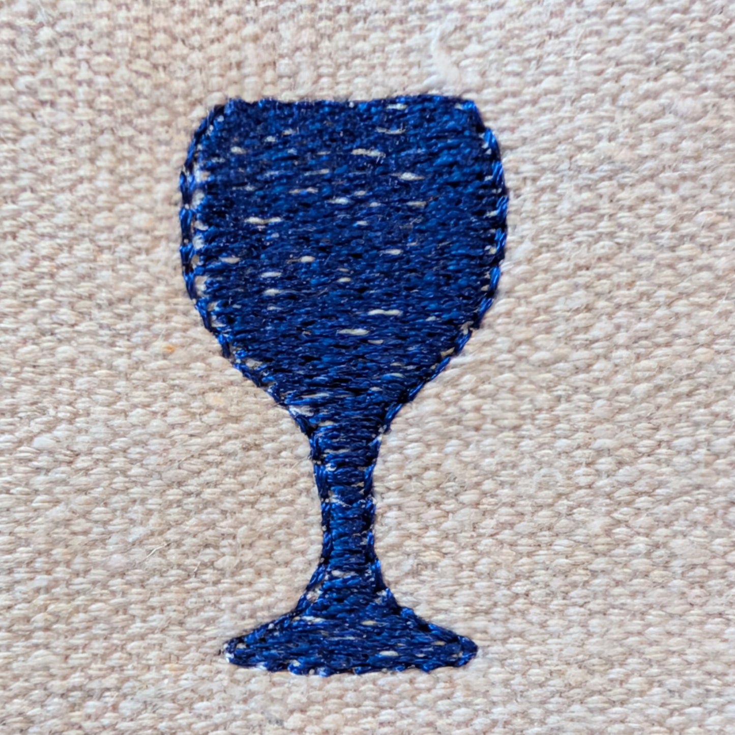 Blue embroidered wine glass shape on beige fabric