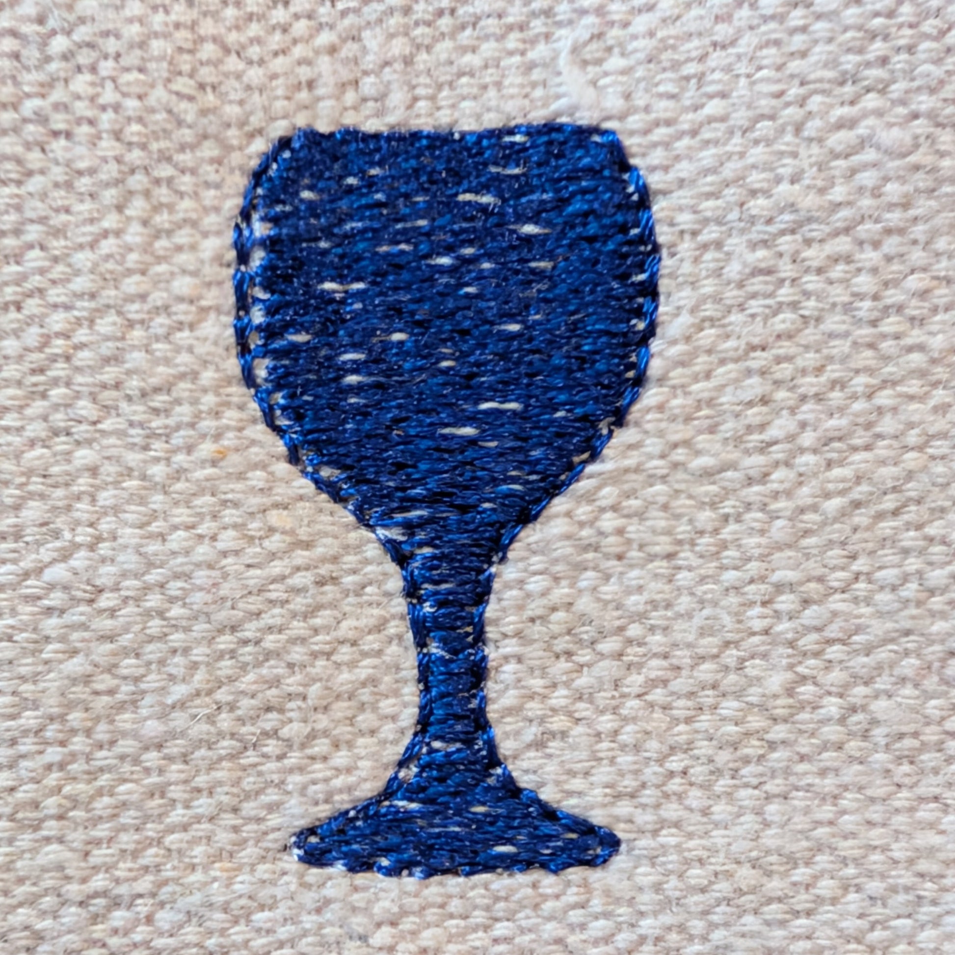 Blue embroidered wine glass shape on beige fabric