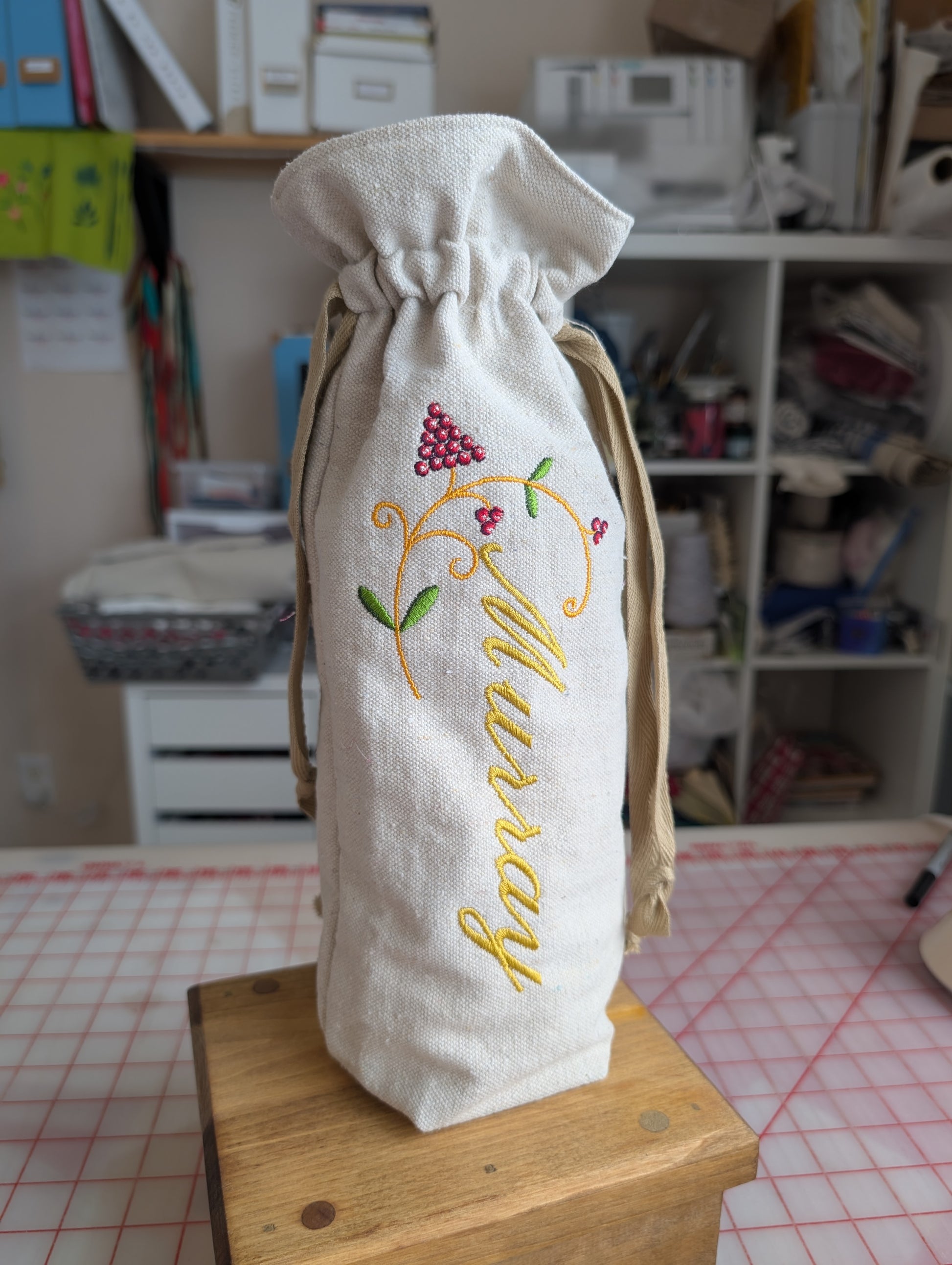 Embroidered fabric bag with 'Murray' on a wooden surface in a room setting.