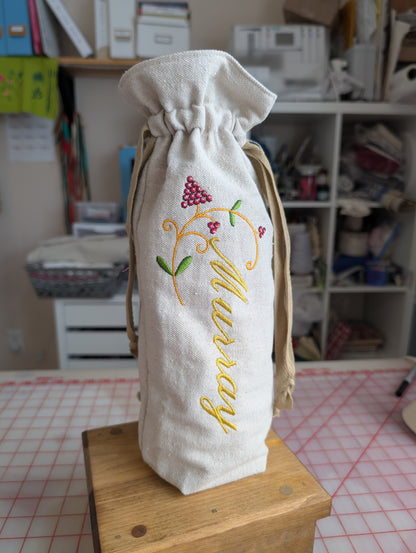 Embroidered fabric bag with 'Murray' on a wooden surface in a room setting.