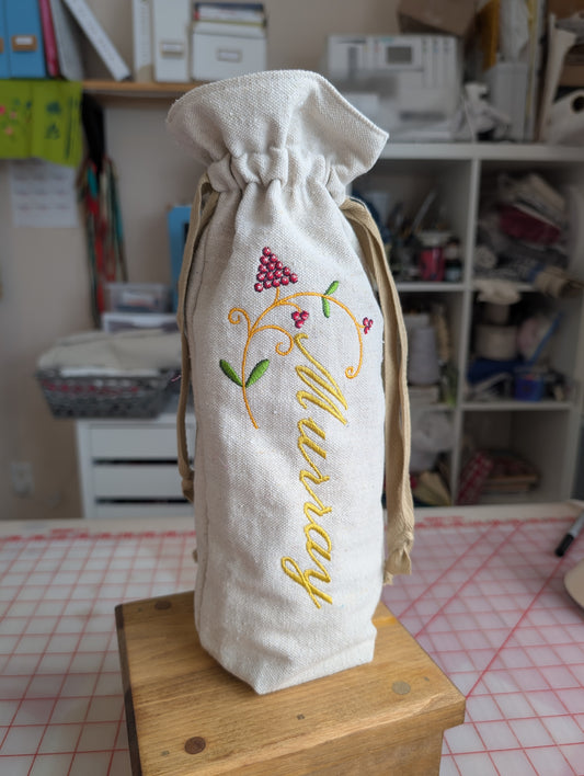 Embroidered fabric bag with 'Murray' on a wooden surface in a room setting.