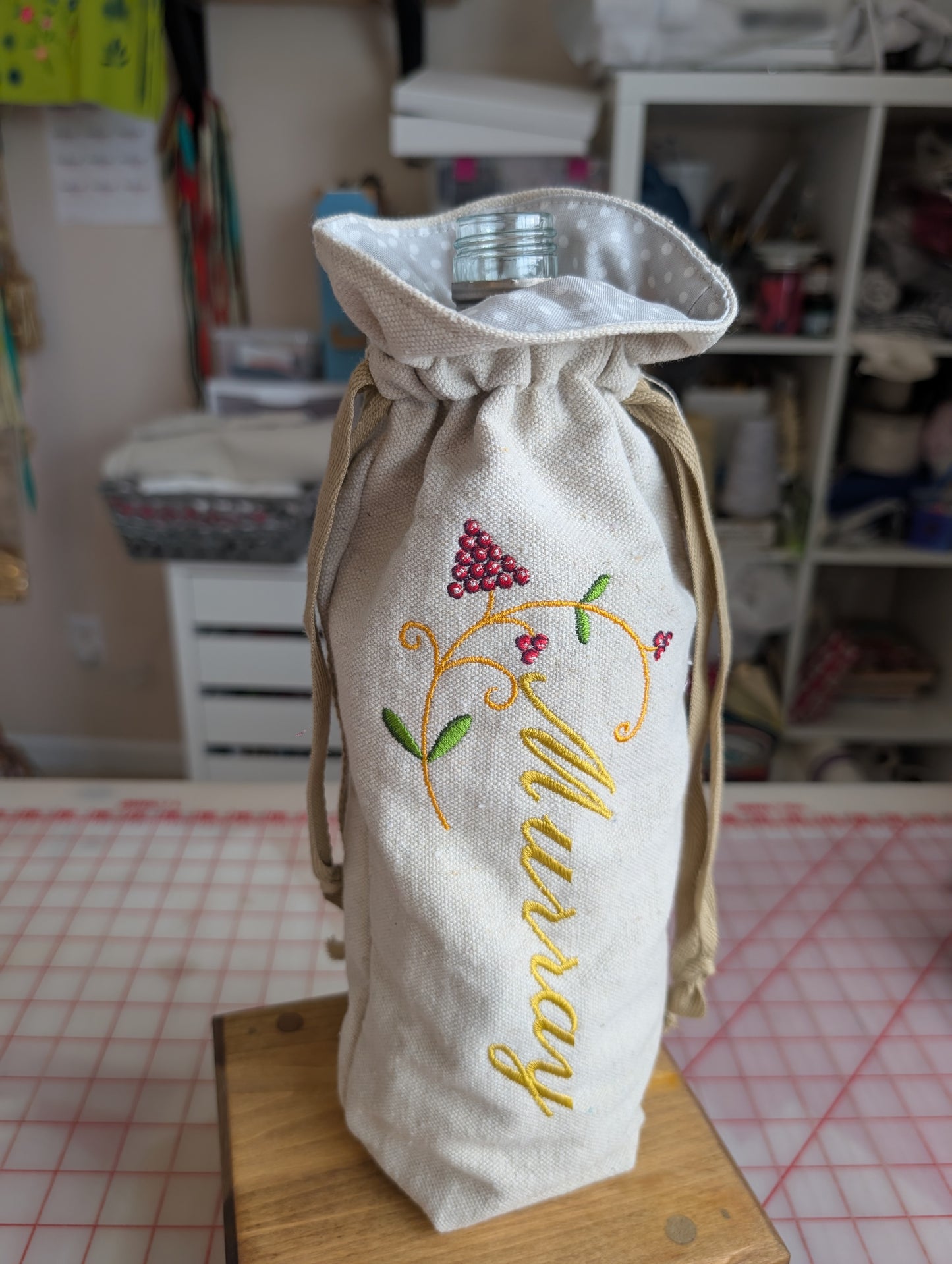 Embroidered fabric bag with 'Murray' text on a table in a workshop setting