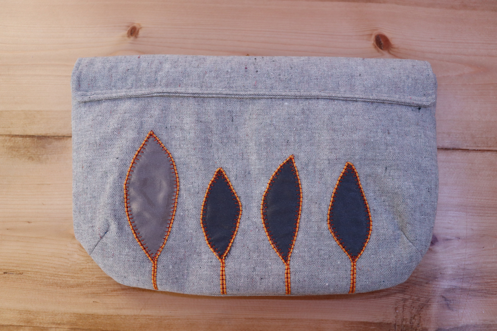 Back of gray handbag clutch with flap and gray leaf applique