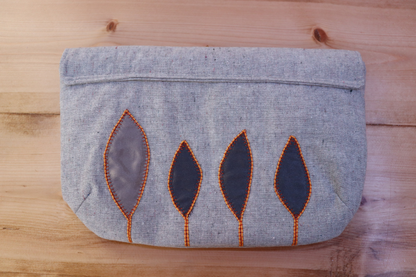 Back of gray handbag clutch with flap and gray leaf applique