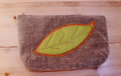 Blush pink clutch handbag with green leaf in appliqué