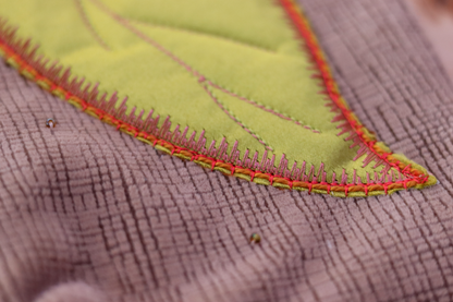 Details of green leaf appliqué on blush pink handbag clutch