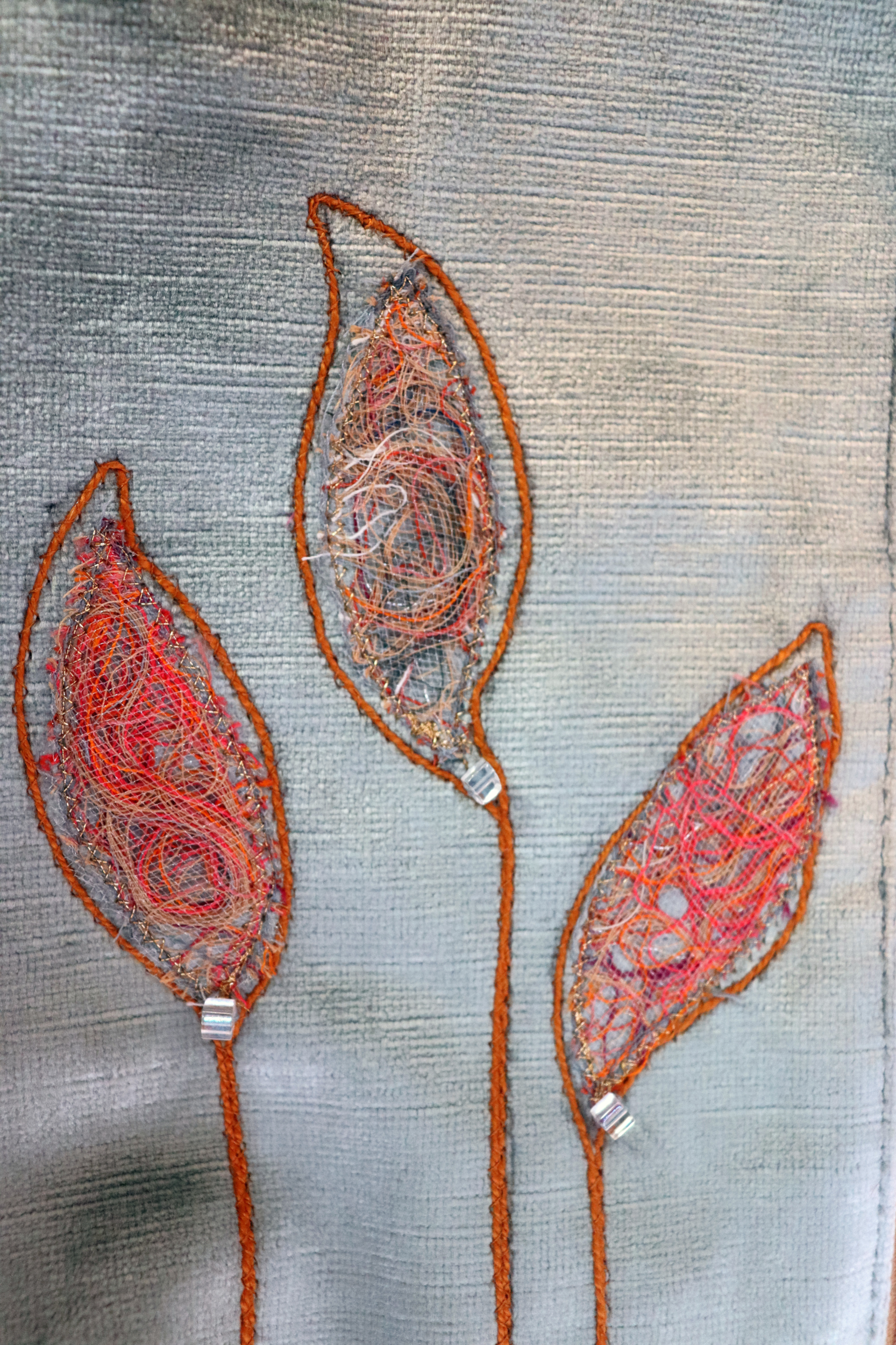 Details of appliqué leaves in gray and orange of grayish and blue handbag clutch