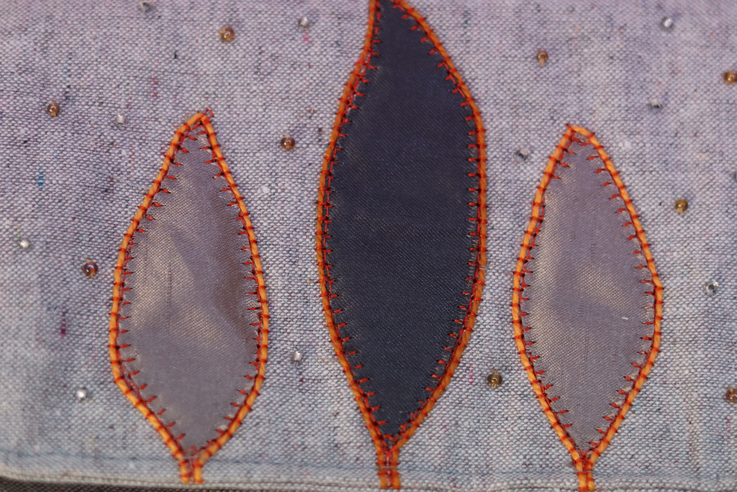 Detail of gray appliqué on gray handbag clutch