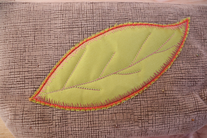 Detail of green appliqué on blush pink handbag clutch 
