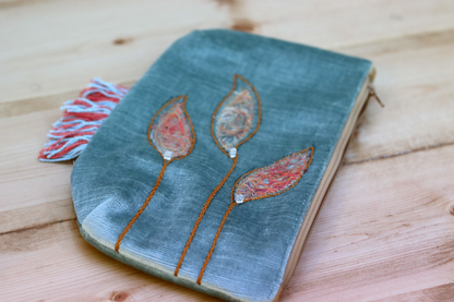 Detail of grayish blue fringe handbag with leaf appliqué