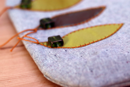 Detail of green glass bead and appliqué of gray and green handbag clutch 